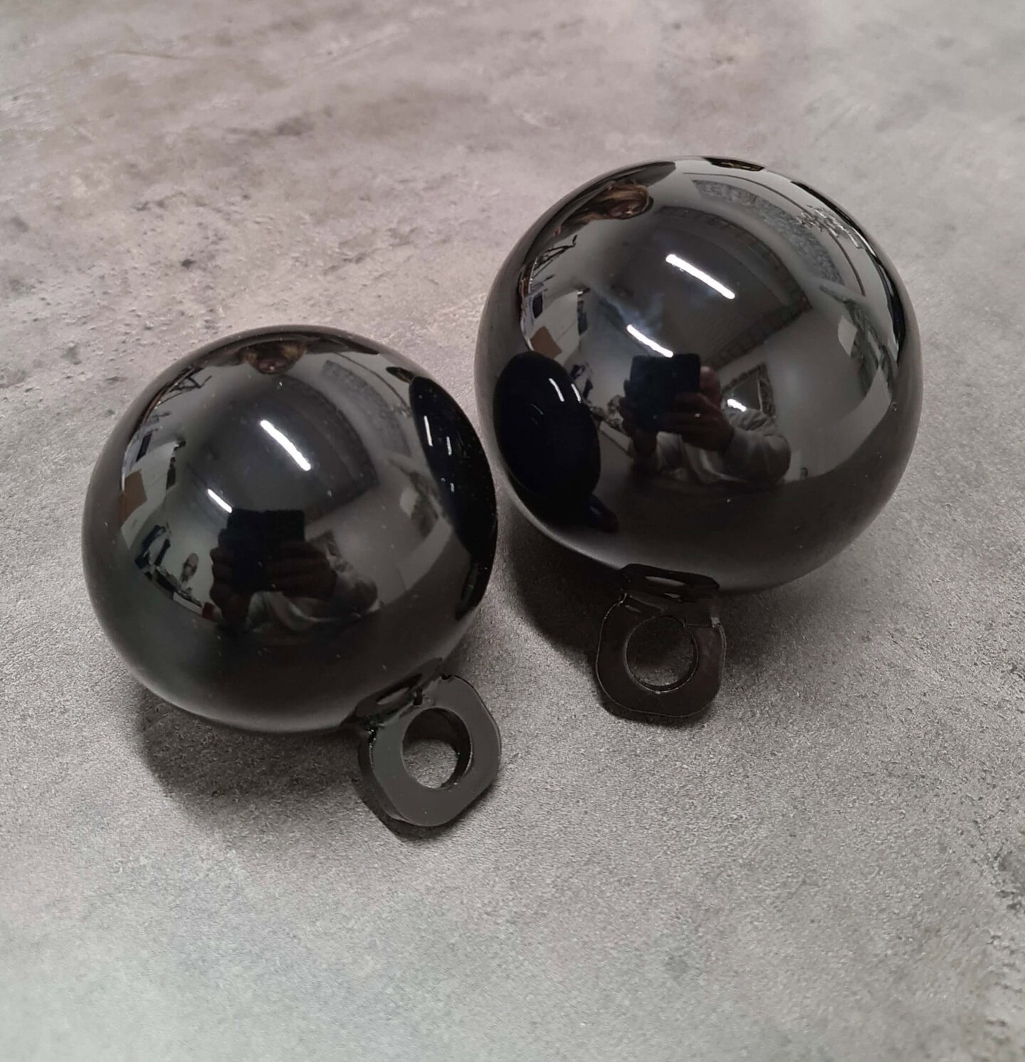 Kiiltävät mustat SportKraft otevoimapallot kahdessa koossa vaalealla taustalla.