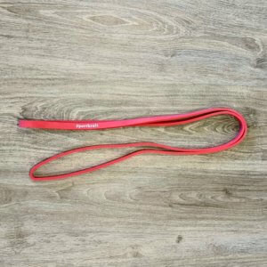 Punainen Powerlifting vastuskuminauha voimaharjoitteluun puisella alustalla.