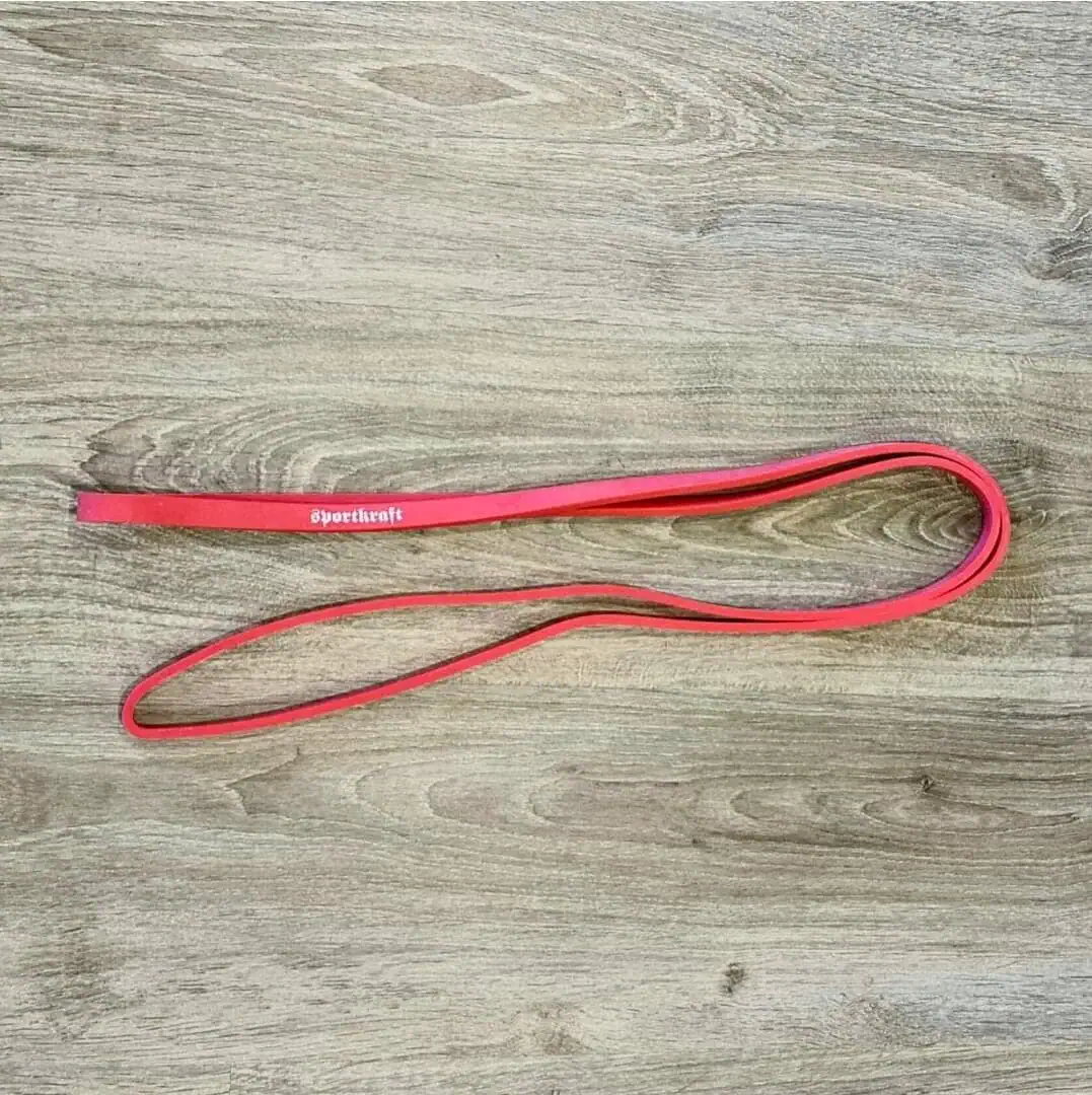 Punainen Powerlifting vastuskuminauha voimaharjoitteluun puisella alustalla.