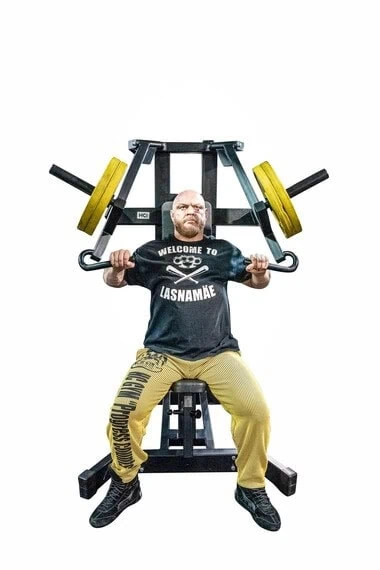 Mies nostaa painoja kuntosalilla.