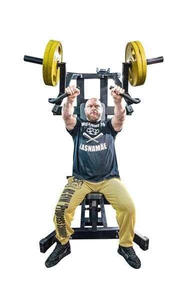 Mies nostaa painoja kuntosalilla.