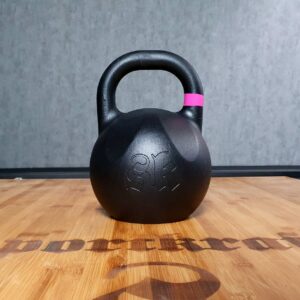 Musta SportKraft-kilpakahvakuula vaalealla puupinnalla, vaaleanpunainen raita kahvassa, tyylikäs treenikuva.