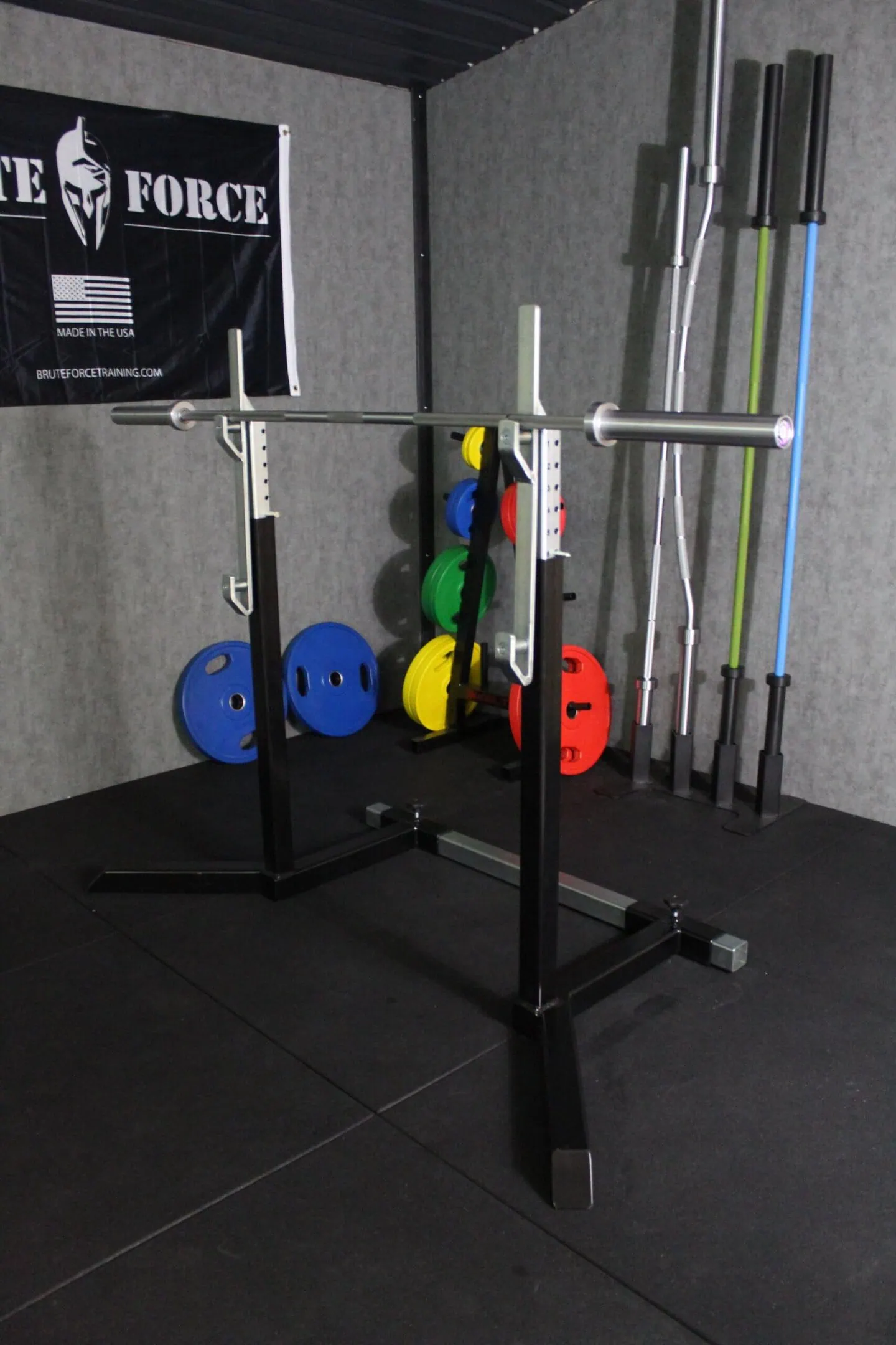 SportKraft kyykkyteline ja värikkäät levypainot modernissa voimaharjoittelutilassa.