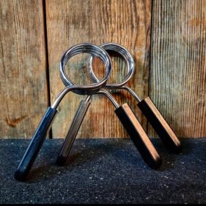 Kiiltävät SportKraft metalliset jousilukot mustilla kahvoilla puutaustaa vasten.