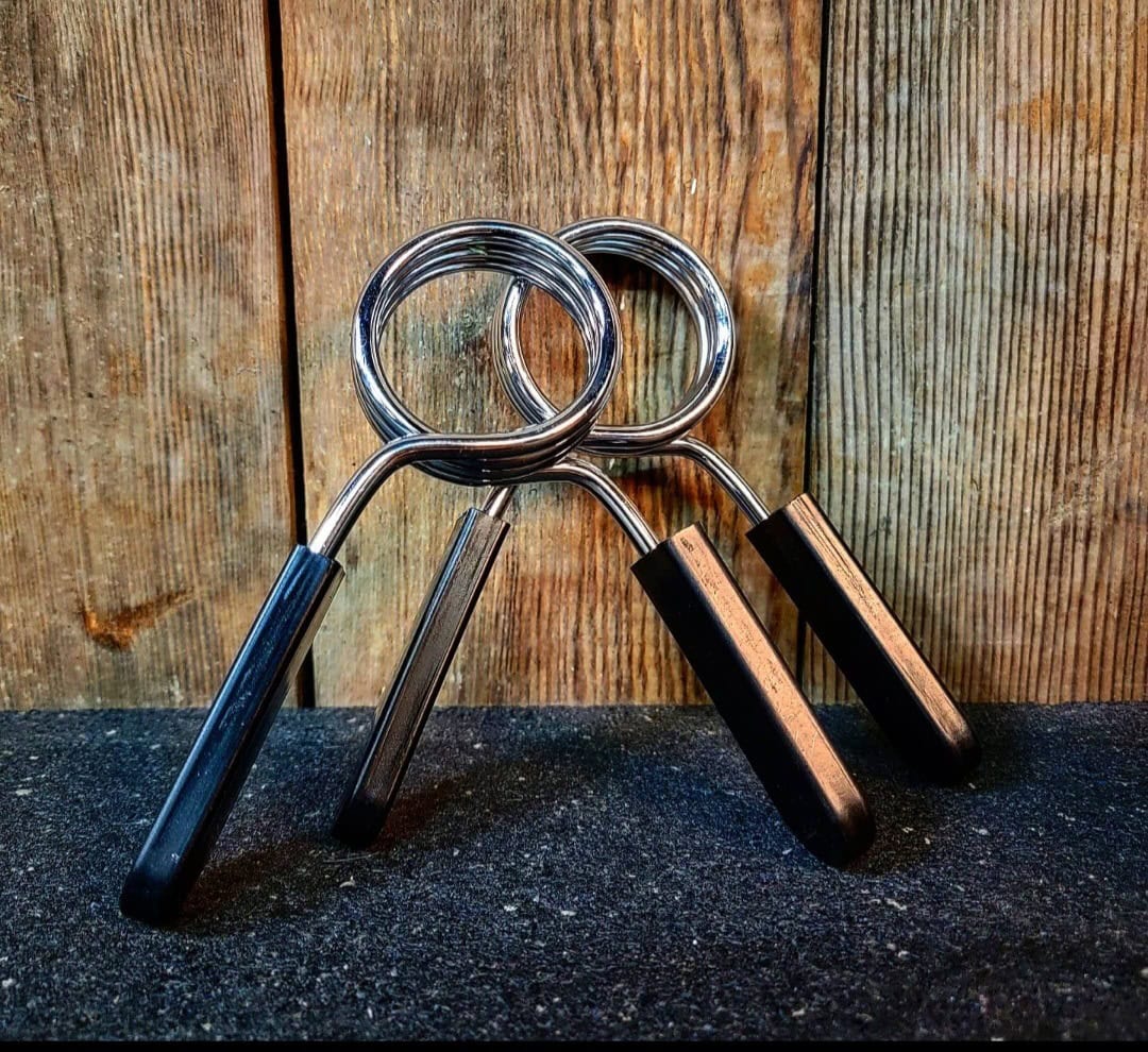 Kiiltävät SportKraft metalliset jousilukot mustilla kahvoilla puutaustaa vasten.