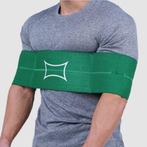 Mies harmaassa t-paidassa käyttää vihreää urheilutukisidettä käsivarrellaan harjoittelun tueksi.