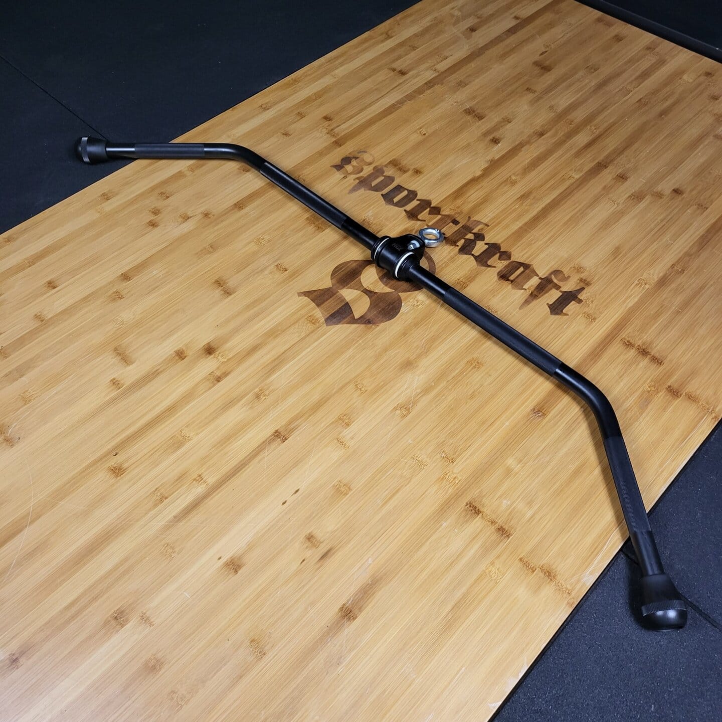 Powercraft kaareva cambered-tanko puulattialla, ergonominen kahva voimaharjoitteluun.