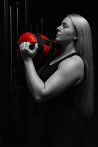 Nainen nostaa painoa salilla.