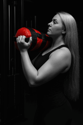 Nainen nostaa painoa salilla.