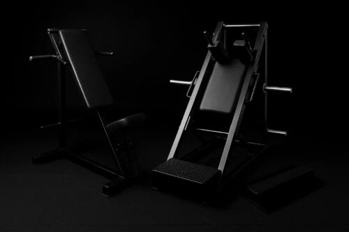 Kaksi mustaa kuntosalilaitetta pimeässä ympäristössä.