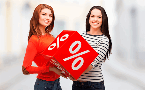 Iloiset naiset esittelevät punaista alennuskuutiota ostosten ja tarjousten merkeissä.